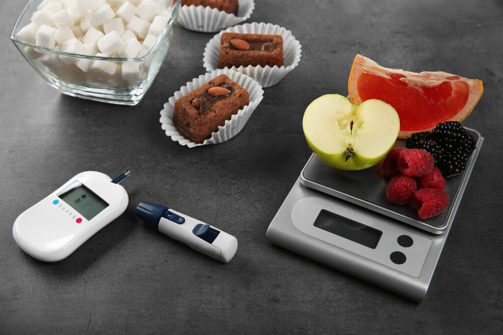 glucose meter with fruits and cookies concept of Managing sugar levels program in Pakistan